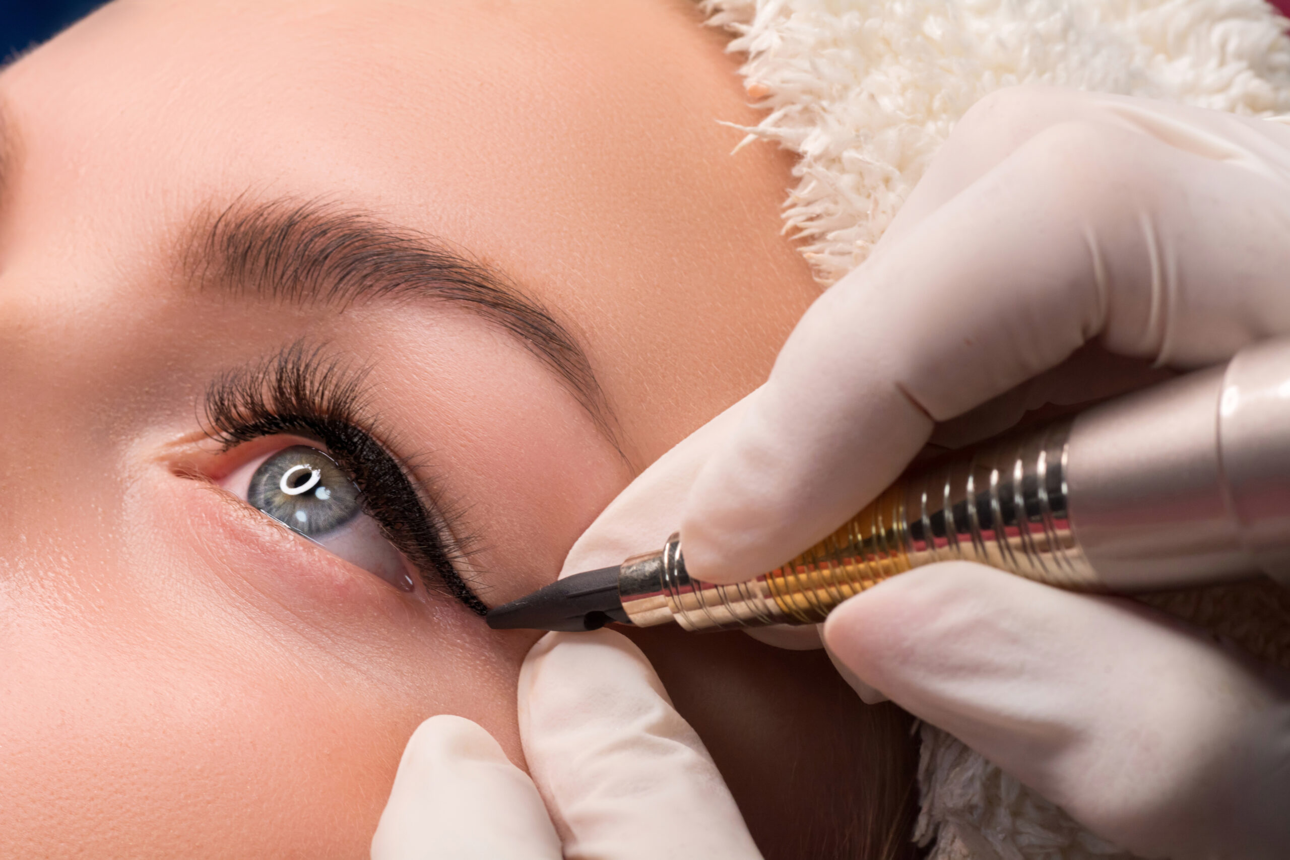 Permanent eye makeup close up shot. Cosmetologist applying tattooing of eyes. Makeup eyeliner procedure.